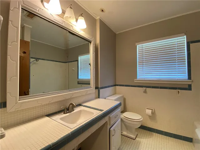 a bathroom with a granite countertop sink a toilet and a mirror