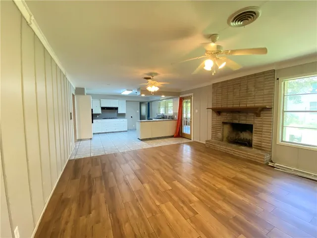 a view of a big room with wooden floor fireplace and windows