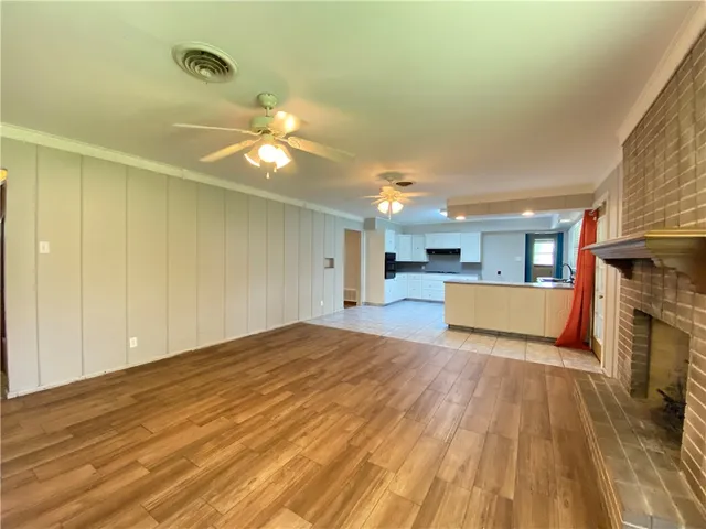 a view of a livingroom with a fireplace a ceiling fan and wooden floor
