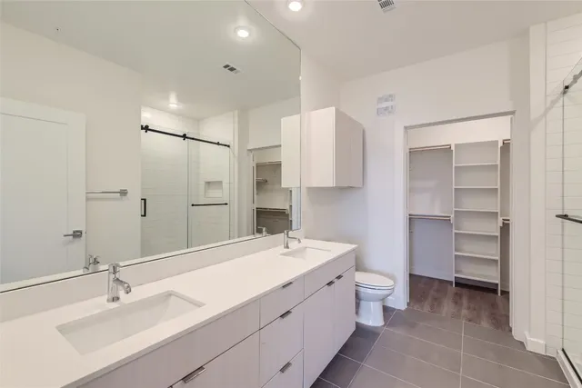 a bathroom with a double vanity sink mirror and toilet
