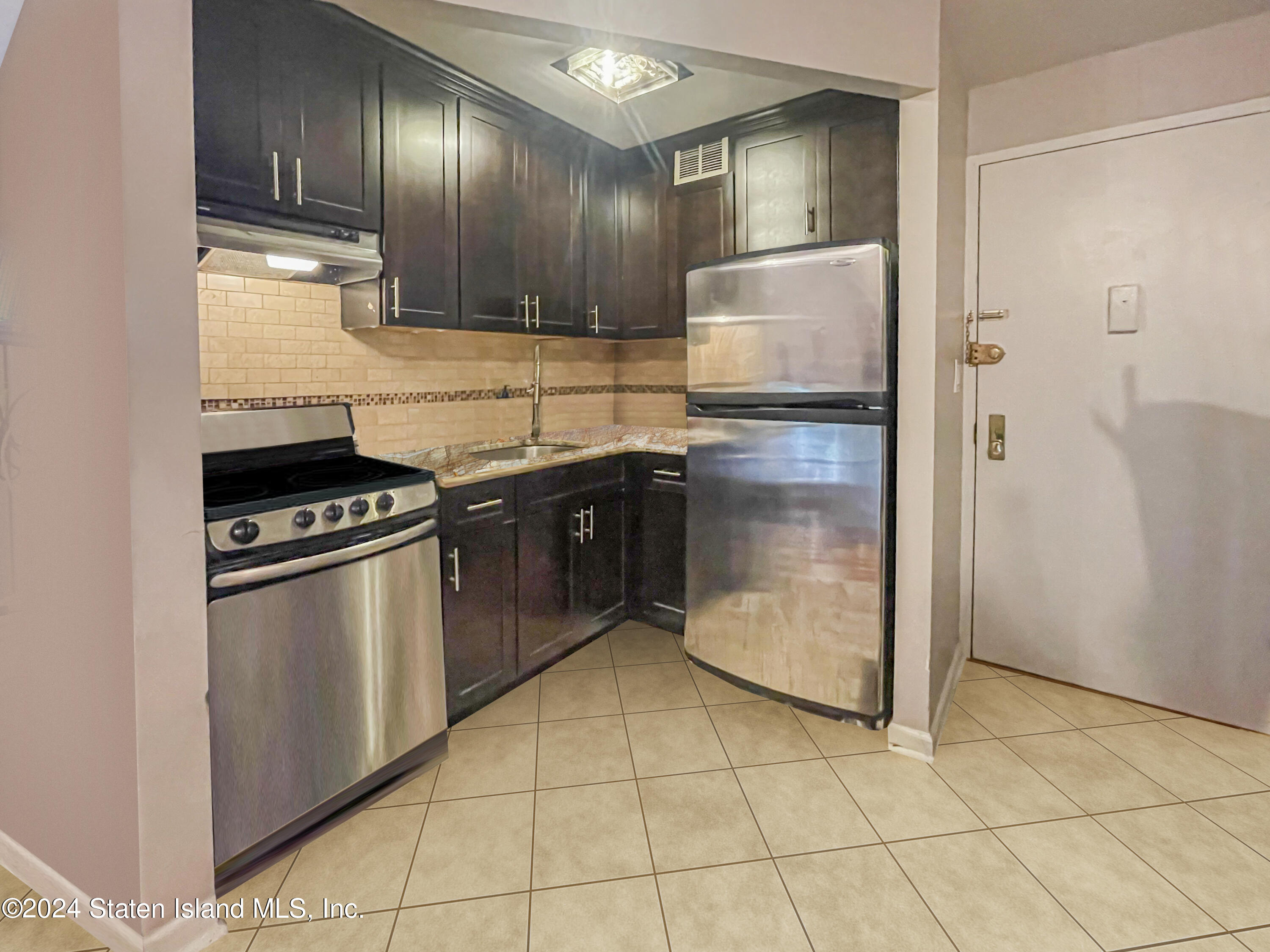175 Zoe Street, Unit 5S Staten Island, NY 10305 - Photo 8 of 15 a kitchen with granite countertop a refrigerator a stove and a sink