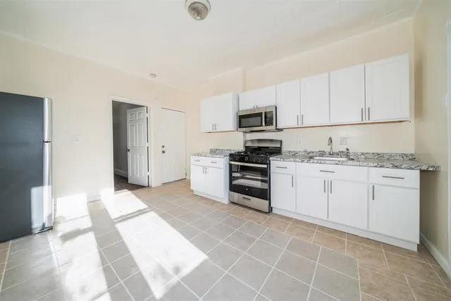 a kitchen with granite countertop white cabinets and stainless steel appliances