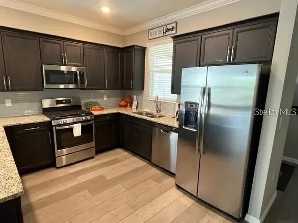a kitchen with stainless steel appliances granite countertop a refrigerator a sink a stove a microwave and wooden cabinets