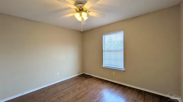 a view of empty room with wooden floor and fan