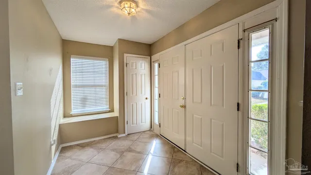 a view of an empty room with window and chandelier fan