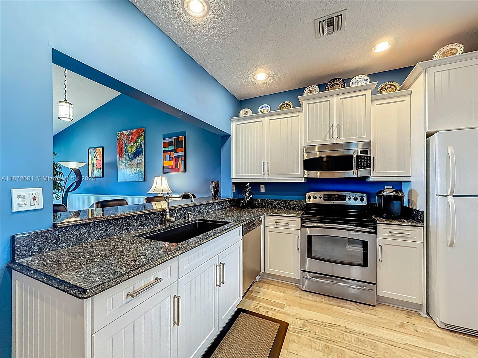 6082 Southeast Landing Way, Unit 11 Stuart, FL 34997 - Photo 44 of 57 a kitchen with stainless steel appliances granite countertop a stove a sink and a refrigerator
