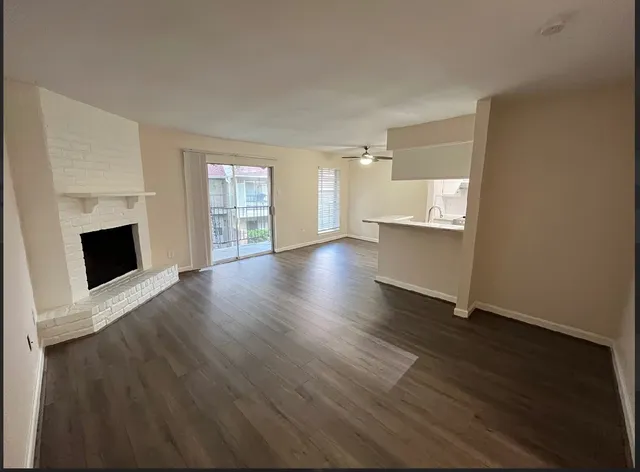 an empty room with wooden floor fireplace and windows