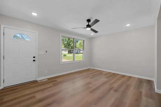a view of empty room with wooden floor and fan