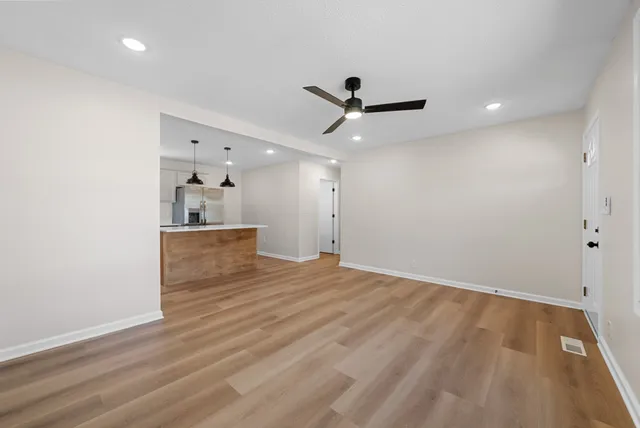a view of empty room with wooden floor and ceiling fan