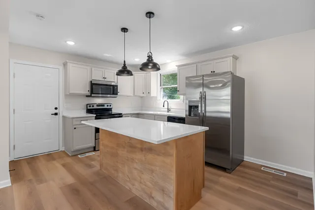 a kitchen with stainless steel appliances granite countertop a sink a counter space a refrigerator and cabinets
