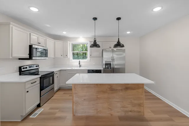 a kitchen with kitchen island a counter top space appliances and cabinets