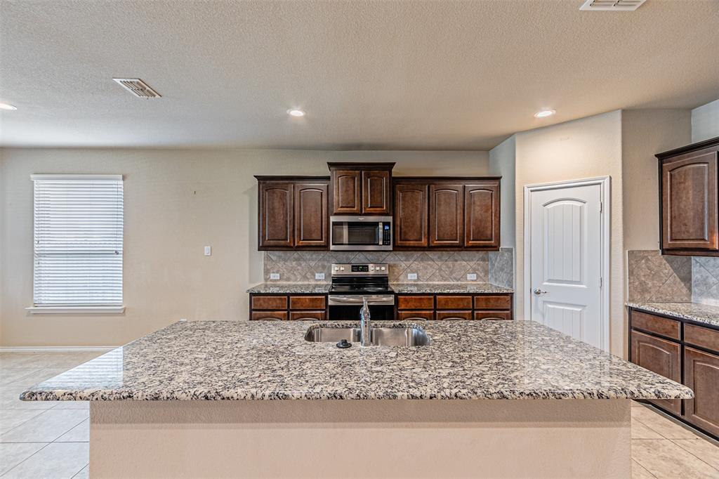 11460 Starlight Ranch Fort Worth, TX 76052 - Photo 6 of 33 a kitchen with stainless steel appliances granite countertop a sink stove and refrigerator