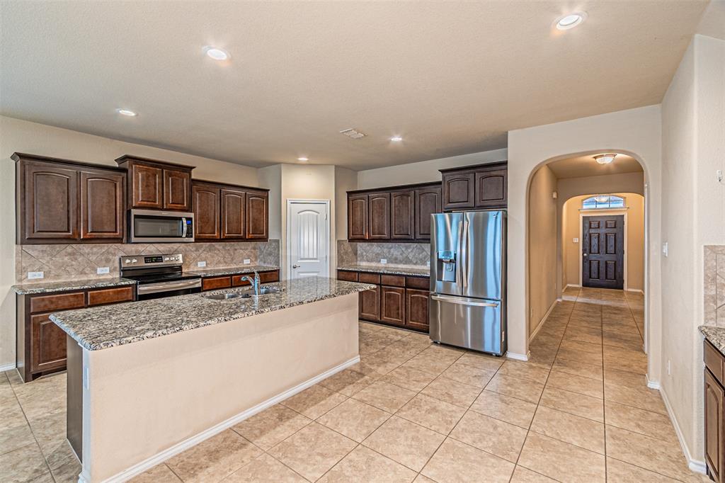 11460 Starlight Ranch Fort Worth, TX 76052 - Photo 7 of 33 a kitchen with stainless steel appliances granite countertop a stove top oven a sink a refrigerator and a granite counter top
