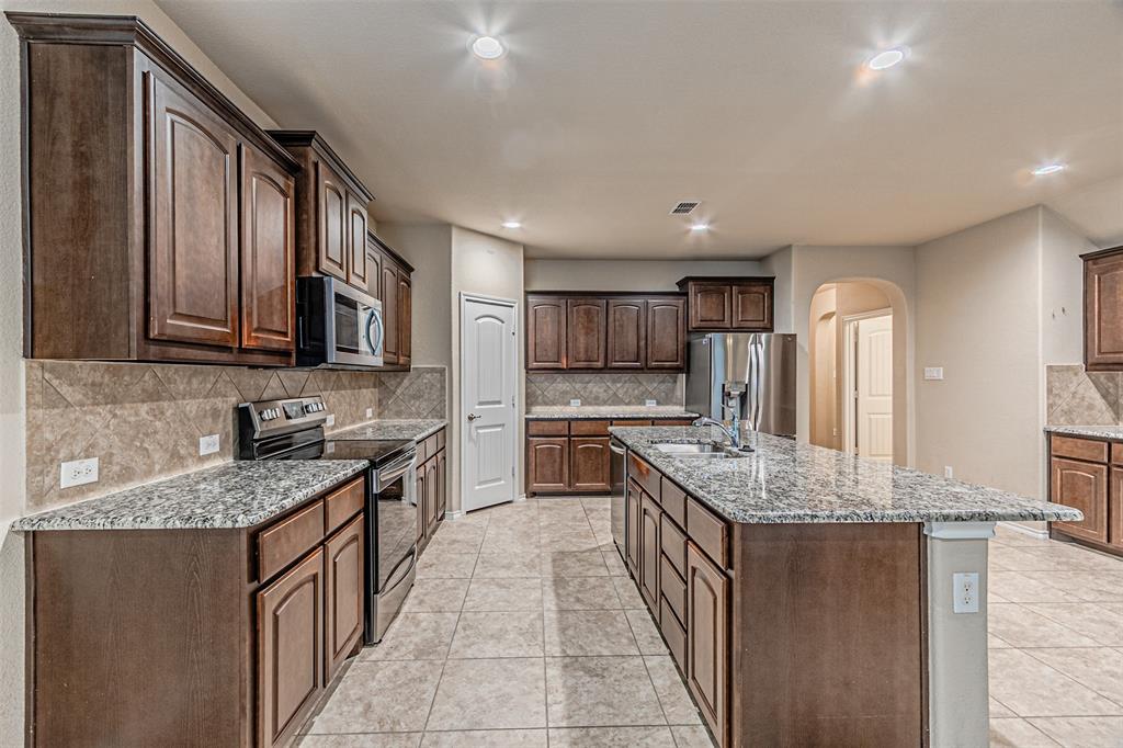 11460 Starlight Ranch Fort Worth, TX 76052 - Photo 9 of 33 a kitchen with stainless steel appliances granite countertop a sink stove and cabinets