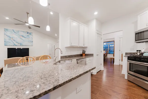 a kitchen with stainless steel appliances granite countertop white cabinets a sink dishwasher a stove and a refrigerator