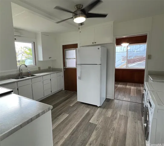a kitchen with a refrigerator a sink and dishwasher with white cabinets