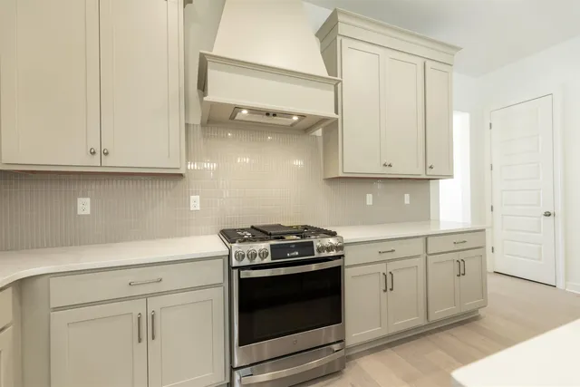 a kitchen with white cabinets and a stove with a sink