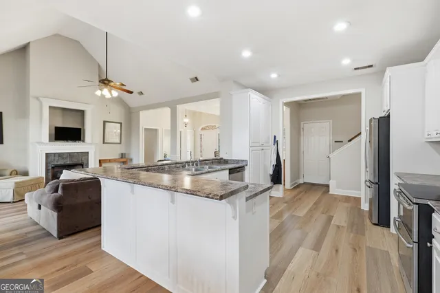 a large kitchen with granite countertop a stove a sink dishwasher and a refrigerator with wooden floor