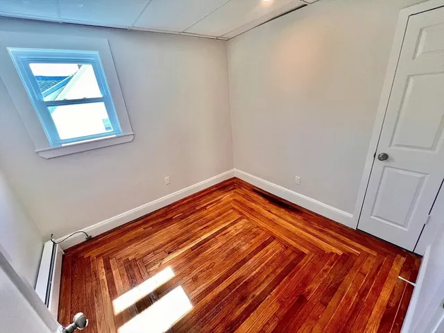 a view of a room with wooden floor and small window