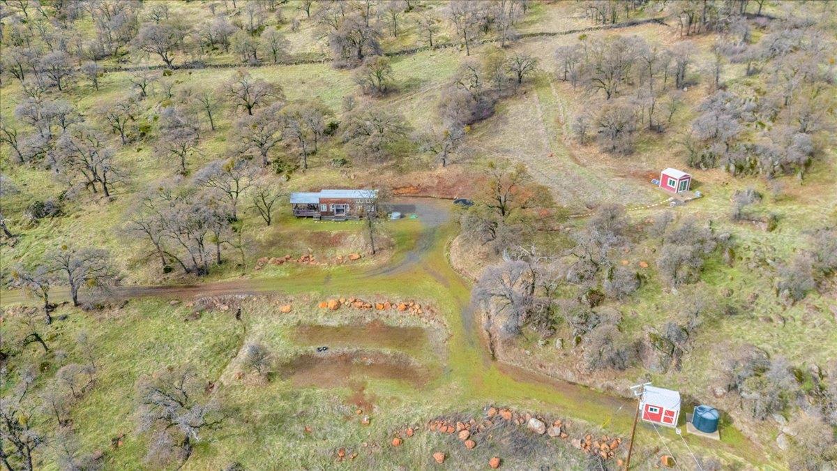 2460 Sulkey Court Copperopolis, CA 95228 - Photo 5 of 91 Aerial of two of the building pads, tiny home, bunk room shed, storage shed, well, and water storage tank.