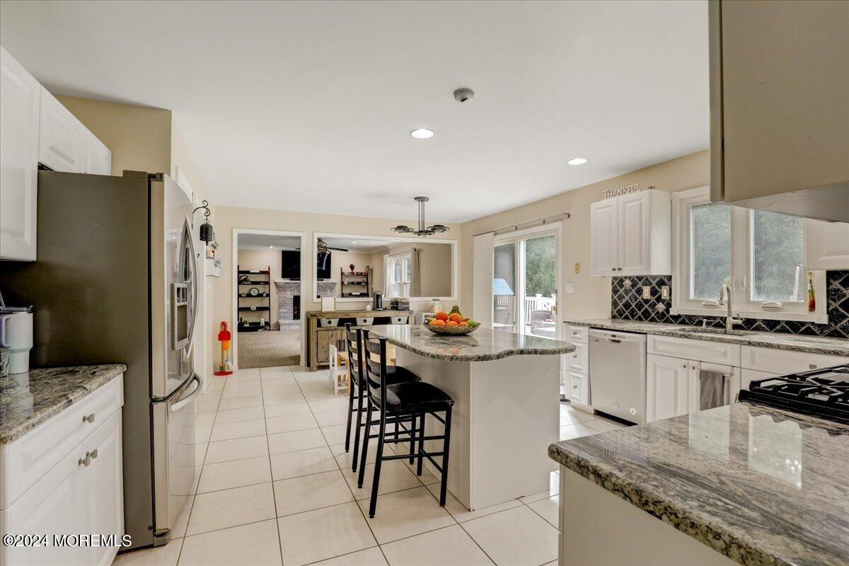 61 Apache Drive Manalapan, NJ 07726 - Photo 11 of 37 a kitchen with stainless steel appliances granite countertop a refrigerator oven a sink a dining table and chairs with wooden floor
