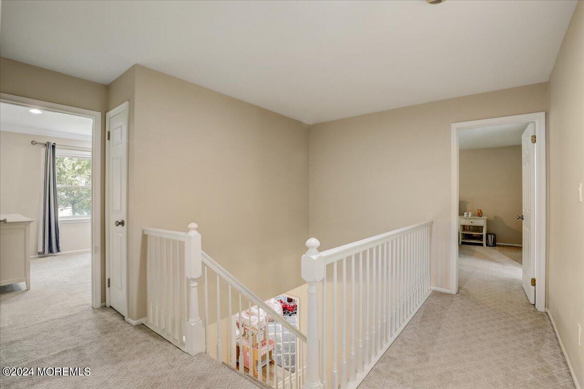 61 Apache Drive Manalapan, NJ 07726 - Photo 20 of 37 a view of a hallway to a livingroom with wooden floor and stairs