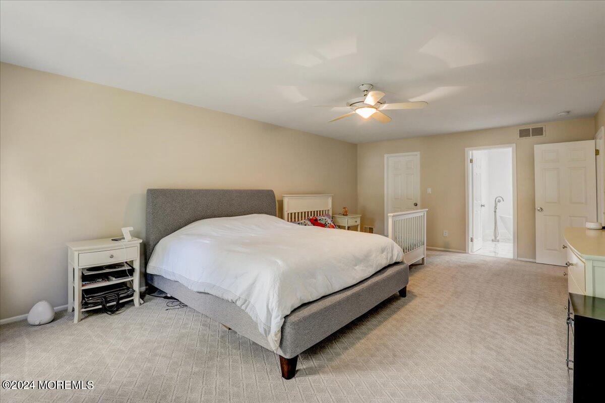 61 Apache Drive Manalapan, NJ 07726 - Photo 22 of 37 a spacious bedroom with a bed and a chandelier