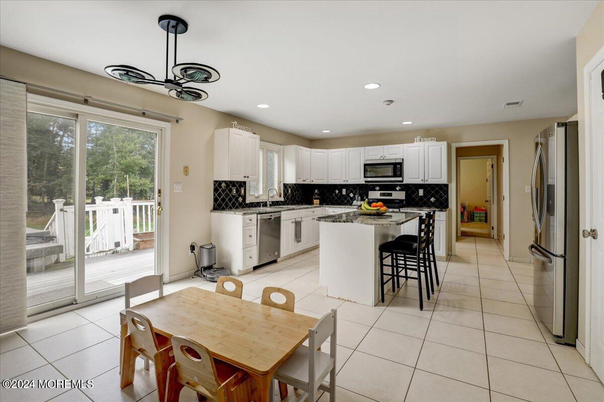 61 Apache Drive Manalapan, NJ 07726 - Photo 9 of 37 a kitchen with stainless steel appliances kitchen island granite countertop a refrigerator a stove top oven and a sink with granite countertops