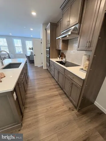 a large kitchen with stainless steel appliances granite countertop a lot of counter space and wooden floors