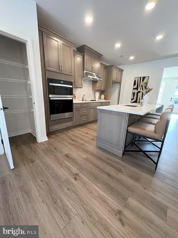 a large kitchen with stainless steel appliances wooden floor and a refrigerator
