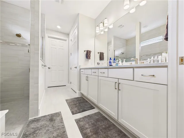 a spacious bathroom with a shower a sink and a mirror