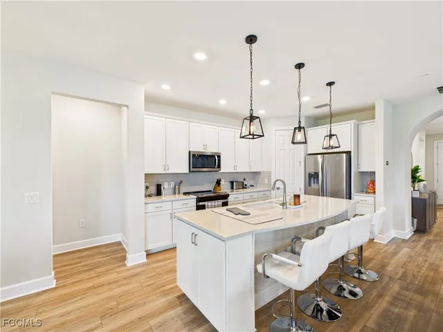 a large kitchen with kitchen island a stove a sink a refrigerator and a wooden floor