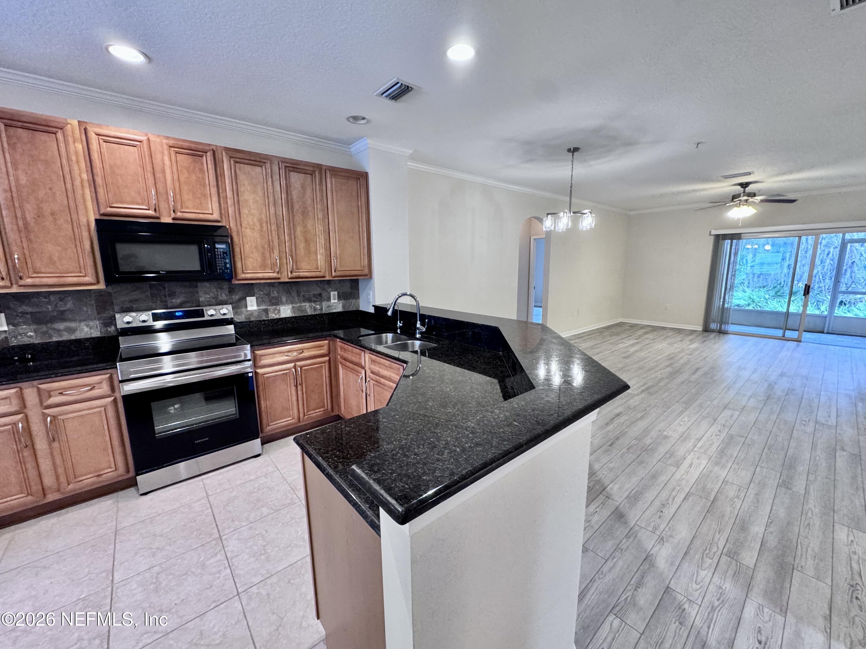 110 Magnolia Crossing Point, Unit 1903 St. Augustine, FL 32086 - Photo 2 of 26 a kitchen with granite countertop a sink a counter top space appliances and cabinets