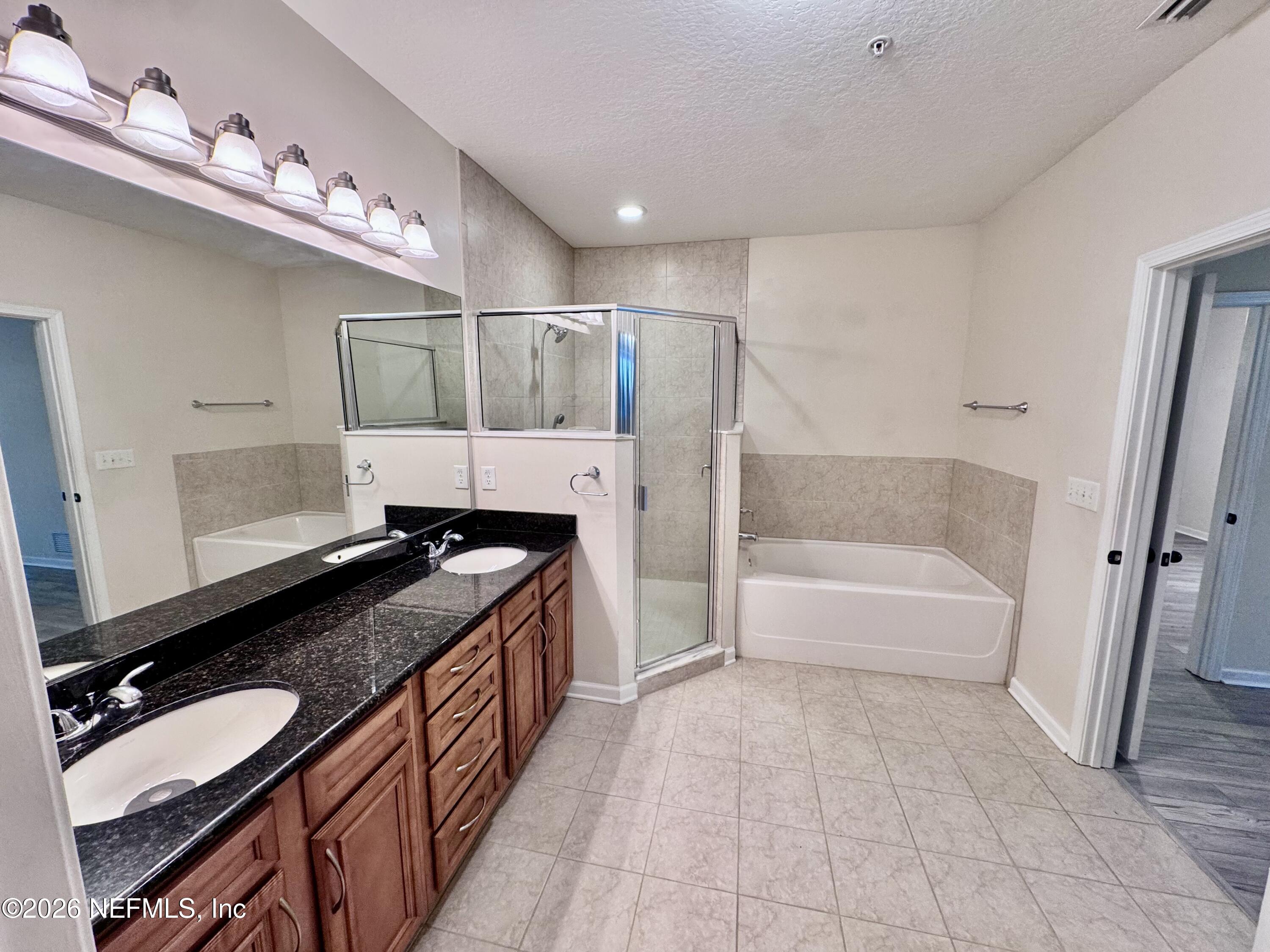 110 Magnolia Crossing Point, Unit 1903 St. Augustine, FL 32086 - Photo 5 of 26 a bathroom with a granite countertop double vanity sink a mirror and a bathtub