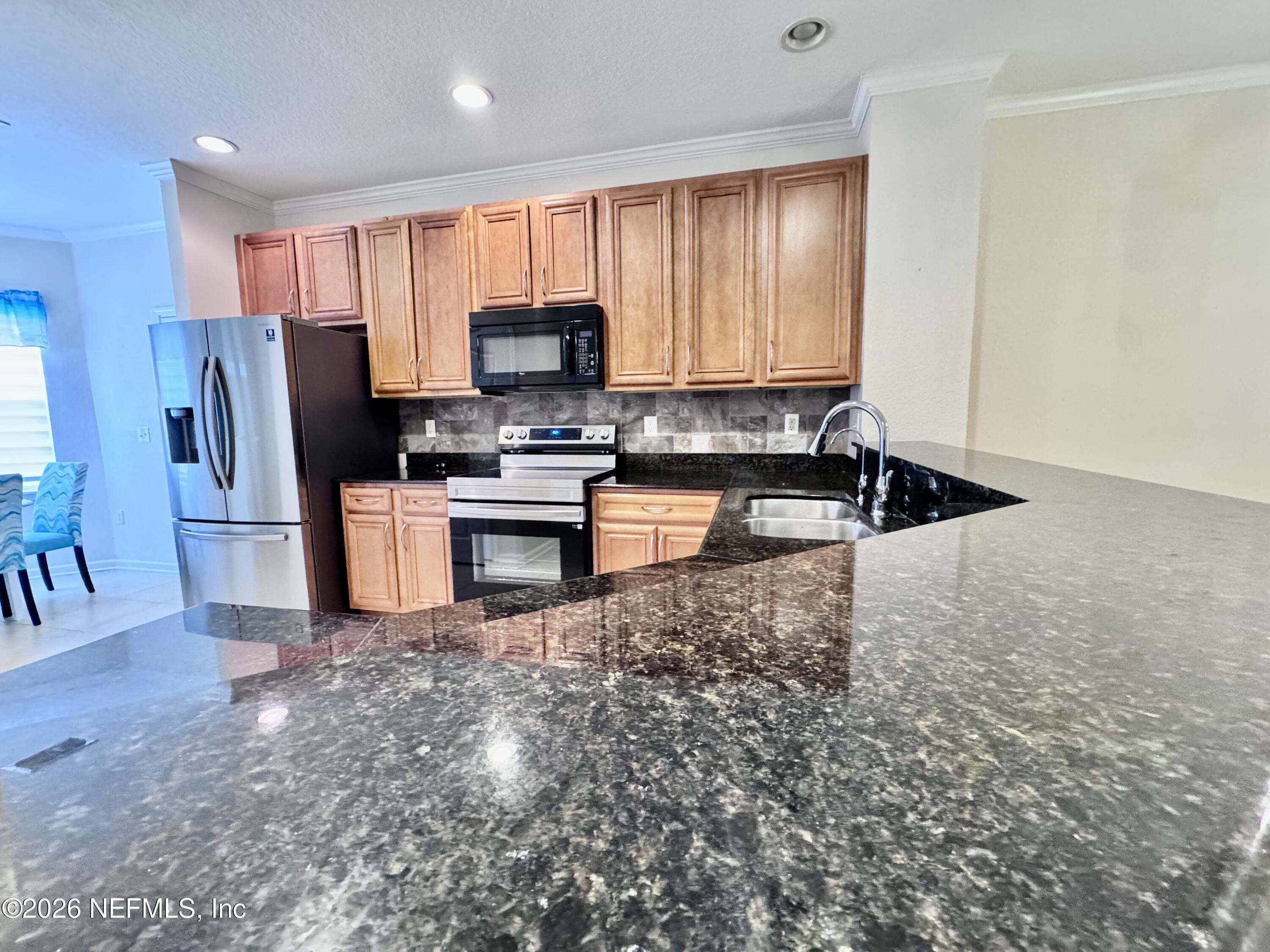 110 Magnolia Crossing Point, Unit 1903 St. Augustine, FL 32086 - Photo 6 of 31 a kitchen with stainless steel appliances granite countertop a stove a sink a refrigerator and a microwave