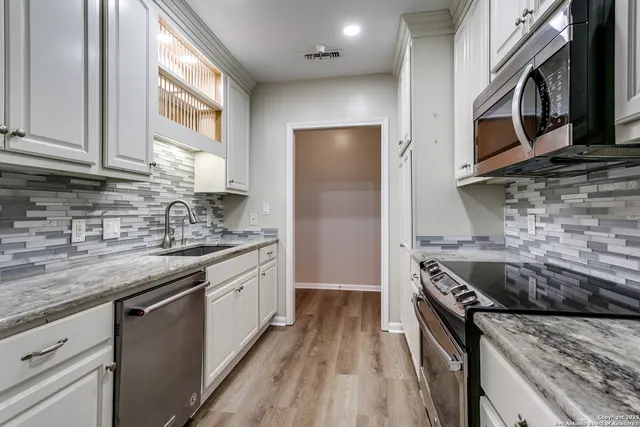 a kitchen with stainless steel appliances granite countertop a stove sink and cabinets