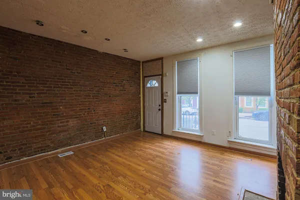 a view of an empty room with wooden floor and windows