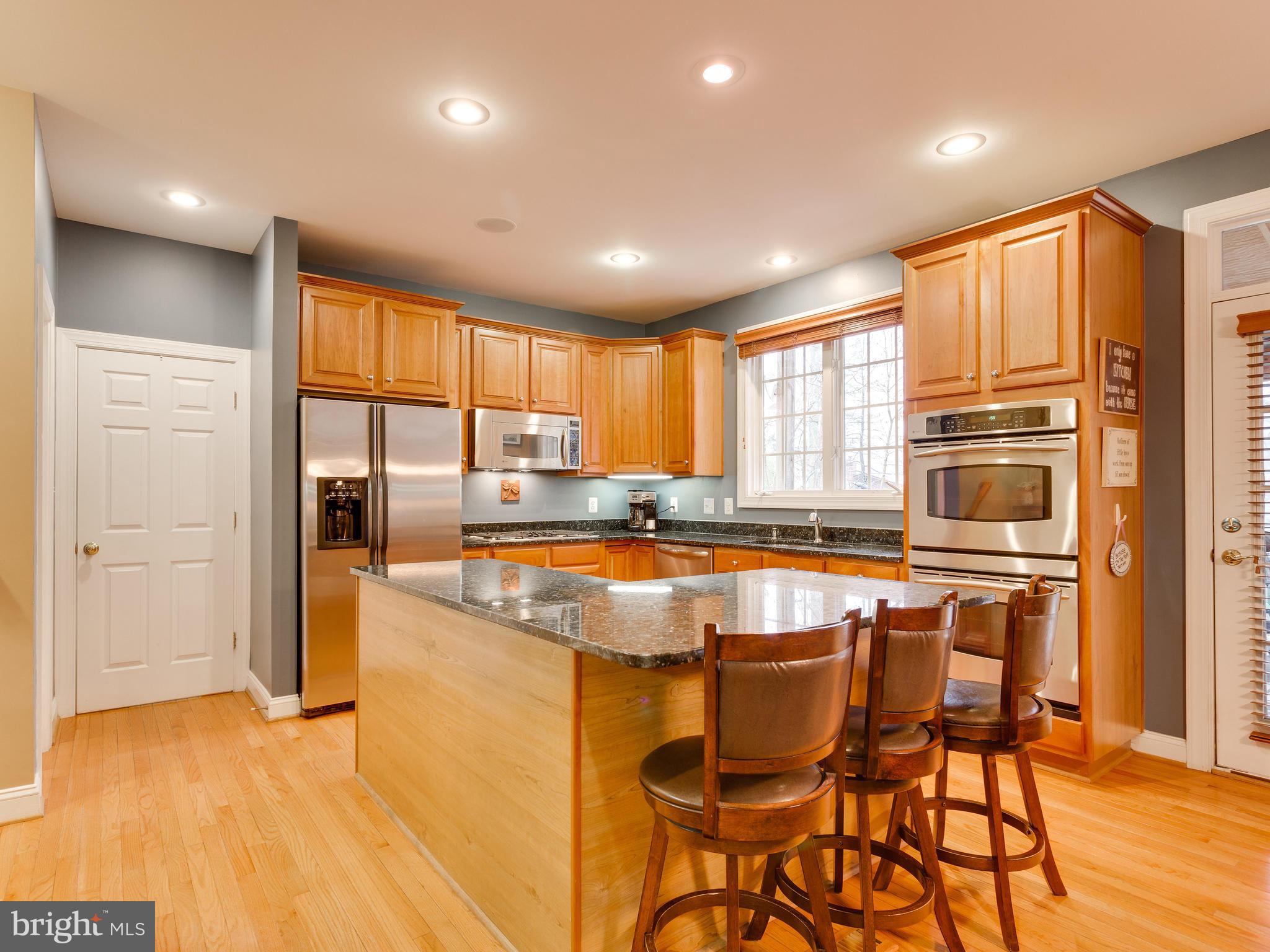 4013 Laurel Road Alexandria, VA 22309 - Photo 11 of 30 a kitchen with stainless steel appliances granite countertop a stove top oven a dining table and chairs with wooden floor
