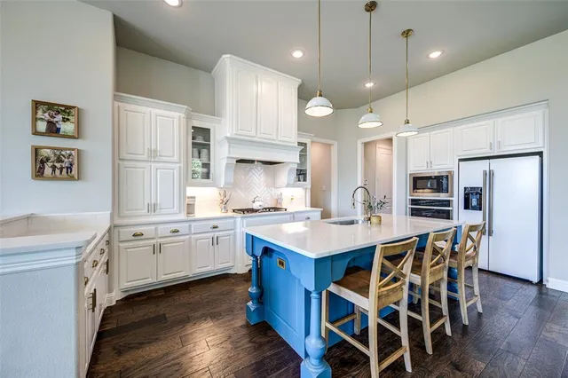 a kitchen with stainless steel appliances kitchen island granite countertop a table chairs sink and cabinets