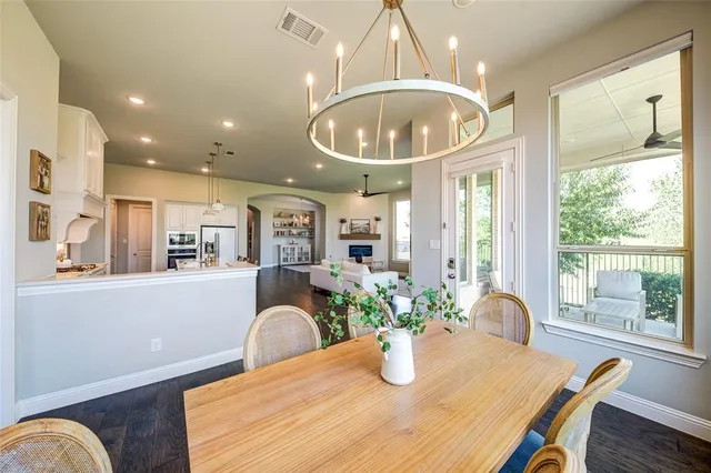 a dining room with wooden floor a chandelier a wooden table and chairs