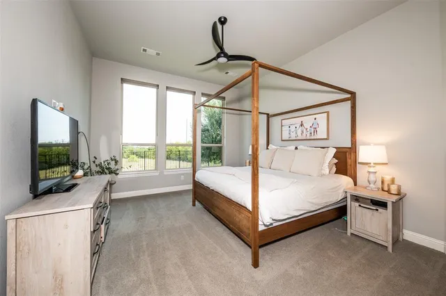 a spacious bedroom with a bed and a flat tv screen on dresser