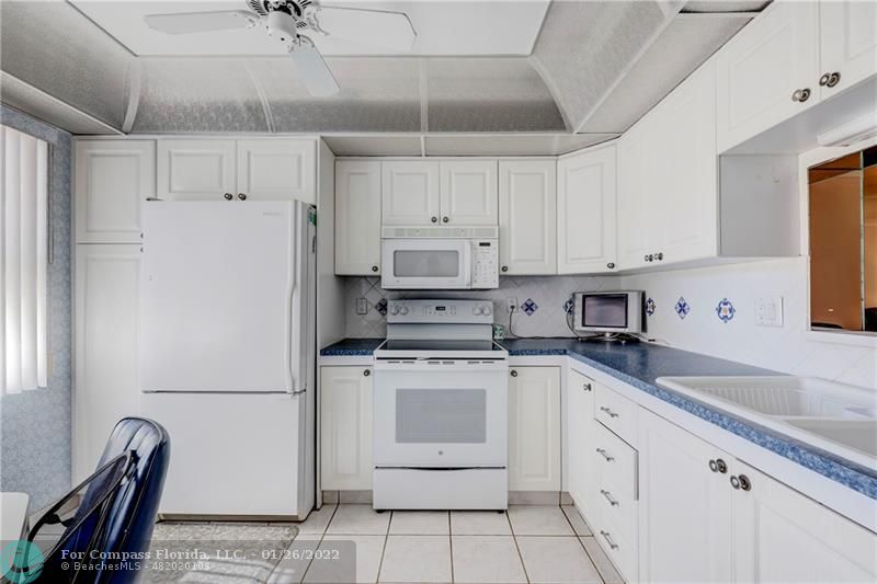 a kitchen with granite countertop white cabinets and white appliances