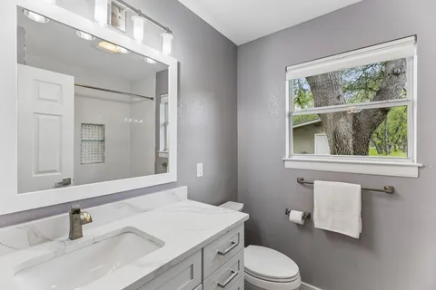 a bathroom with a sink vanity mirror and toilet