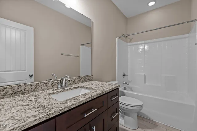 a bathroom with a granite countertop sink a toilet and shower