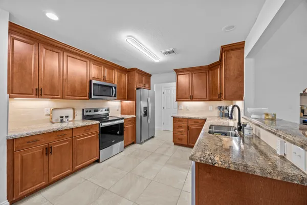 a kitchen with stainless steel appliances granite countertop wooden cabinets a stove top oven a sink and dishwasher