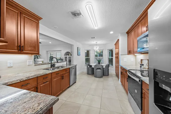 a large kitchen with stainless steel appliances granite countertop lots of counter top space a sink a window and stainless steel appliances