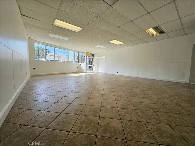 an empty room with chandelier fan and windows