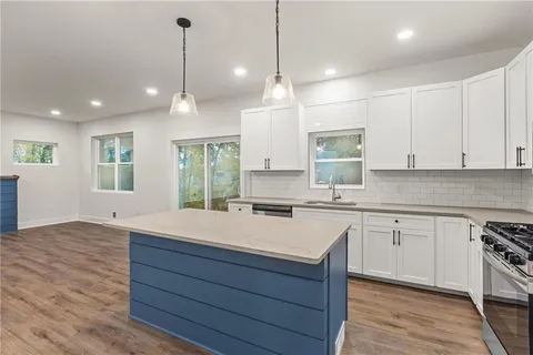 a kitchen with a stove a sink and wooden floor