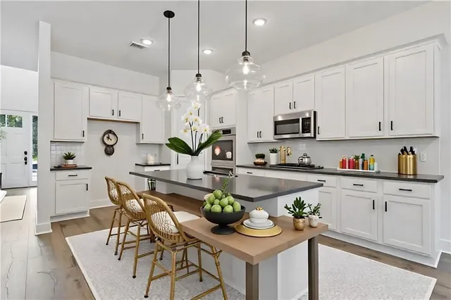 a kitchen with stainless steel appliances kitchen island granite countertop a white table and chairs in it