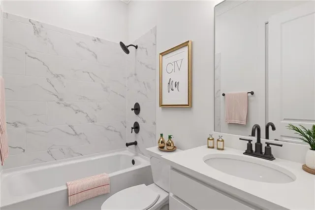 a bathroom with a granite countertop bathtub sink vanity mirror and toilet